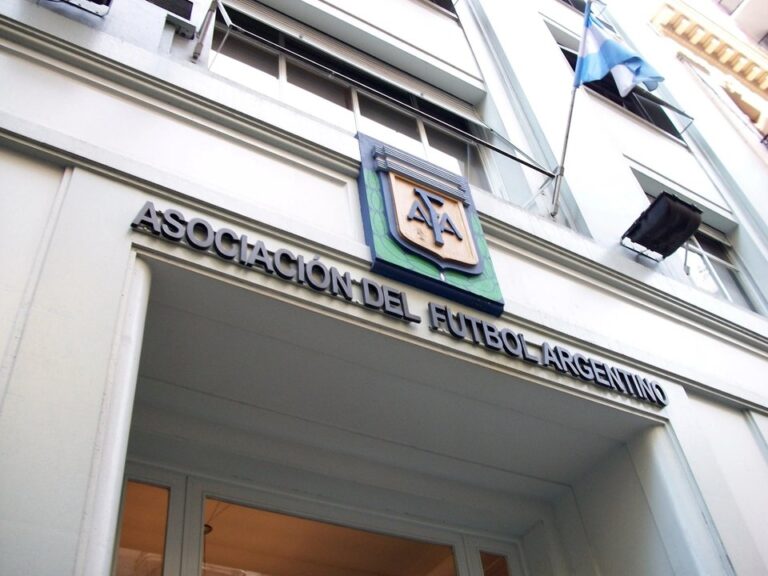 Fachada de un club de fútbol argentino con presencia policial durante un allanamiento judicial.