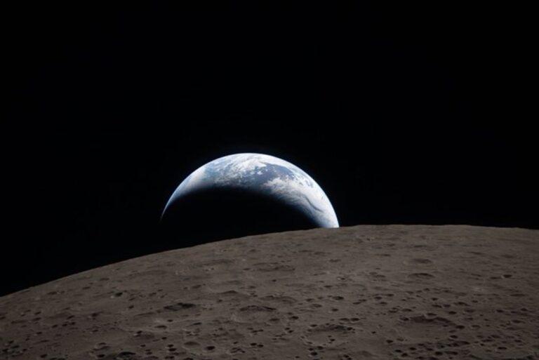 Astronauta del Apolo 11 en la superficie lunar junto a la bandera de Estados Unidos.