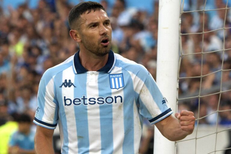 Escudos de Racing Club y San Lorenzo de Almagro sobre un fondo de cancha de fútbol
