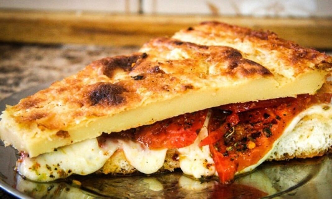 Porción de pizza sobre una mesa, con fondo de pizzería tradicional y moderna.