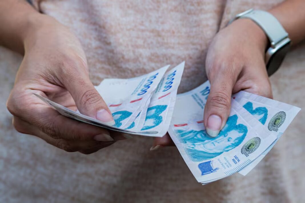 Ilustración de útiles escolares y un sobre con dinero, representando el refuerzo de la Ayuda Escolar.