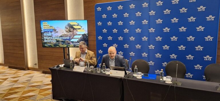 Participantes en un foro de aviación internacional con logos de IATA y Wings of Change Americas de fondo.