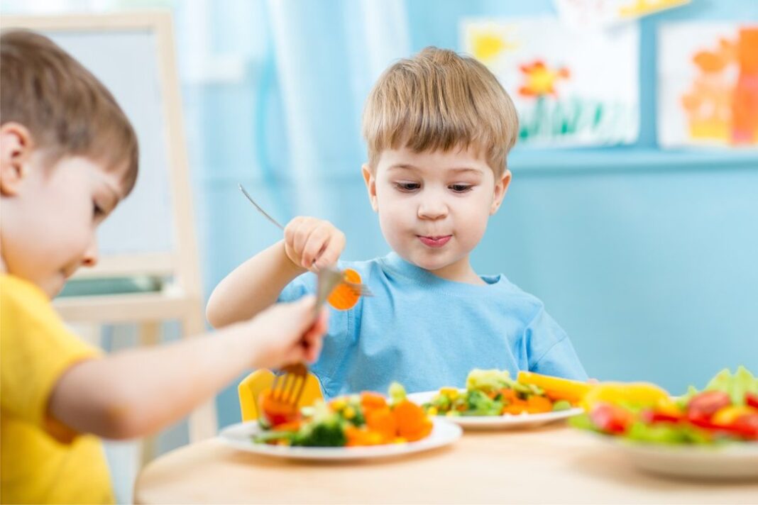 Niño pequeño frente a un plato de comida variada, mostrando indecisión