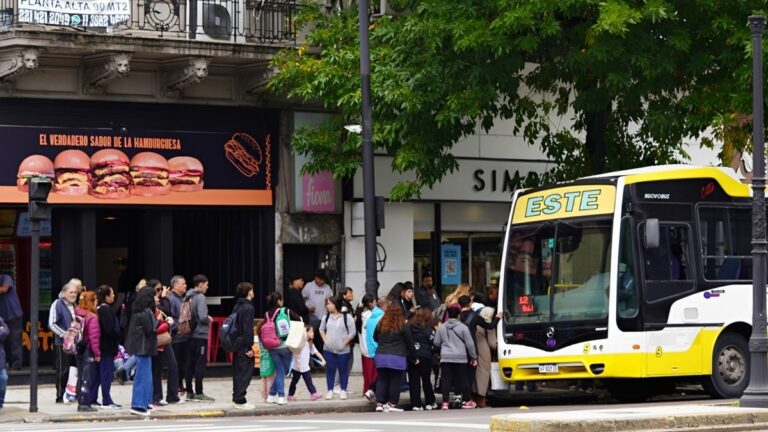 Personas abordando un colectivo y un tren en el AMBA, con carteles de tarifas actualizadas