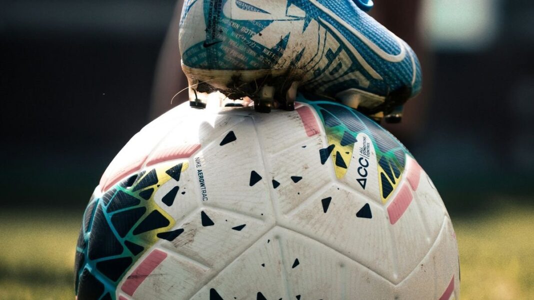 Balón de fútbol sobre fondo de banderas de países sede del Mundial 2026
