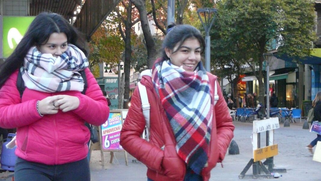 Personas abrigadas caminando en una calle con cielo nublado en la provincia de Buenos Aires