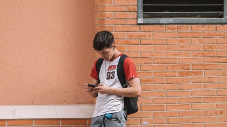 Adolescentes usando teléfonos móviles en un aula escolar
