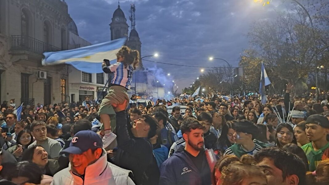 Multitud festejando en la calle con banderas argentinas