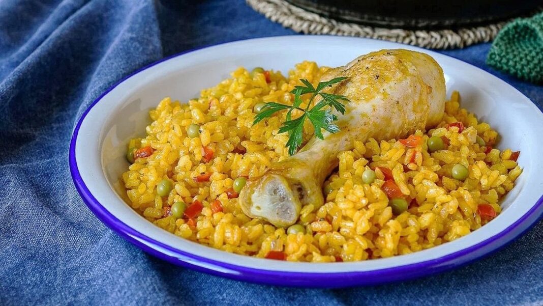 Arroz con pollo en una sartén, con ingredientes y vegetales